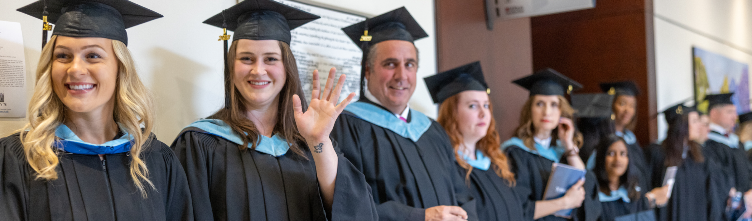 A long line of graduates standing together against a wall