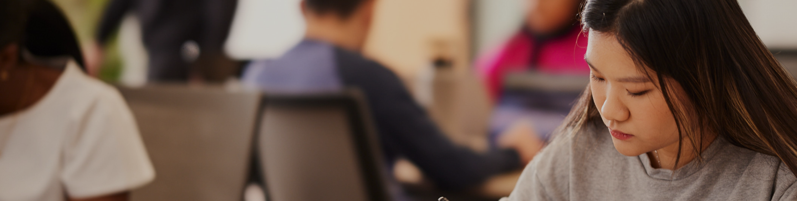 International student working at a desk in a room with other students