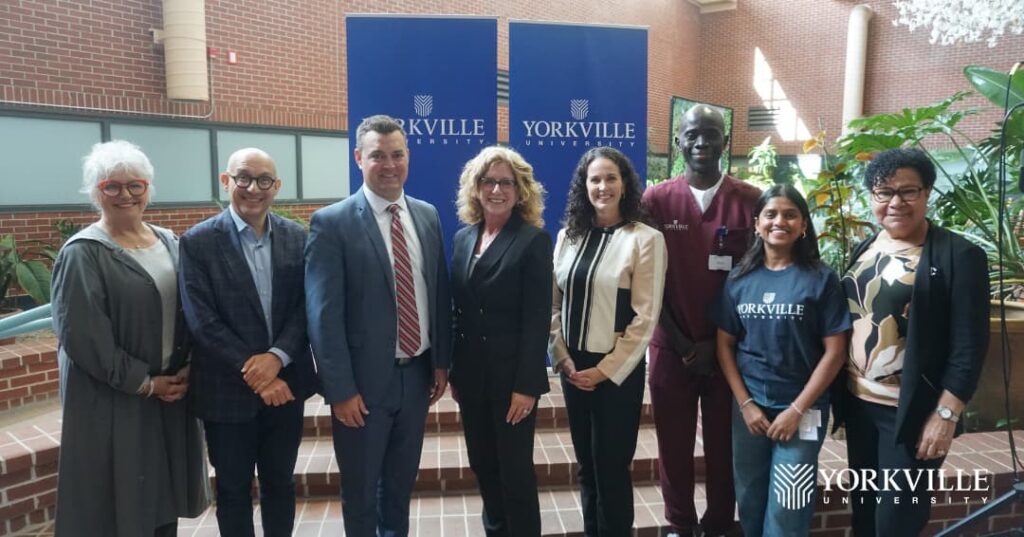 Key members of Beal University and Yorkville University posing in front of Yorkville University banners.